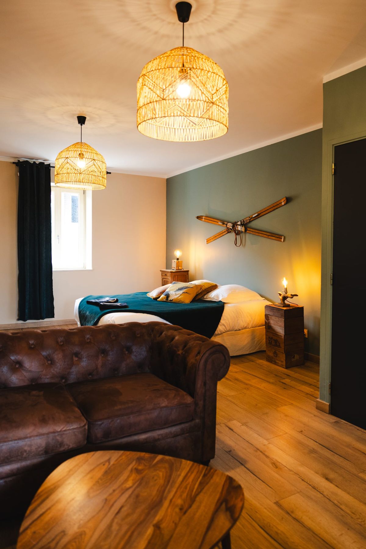 Bedroom suite with a leather chesterfield sofa, teal accent wall and vintage skis mounted above the bed