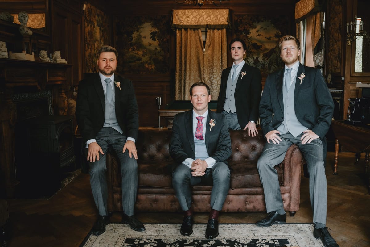 Four groomsmen posing together in the wood-panelled salon