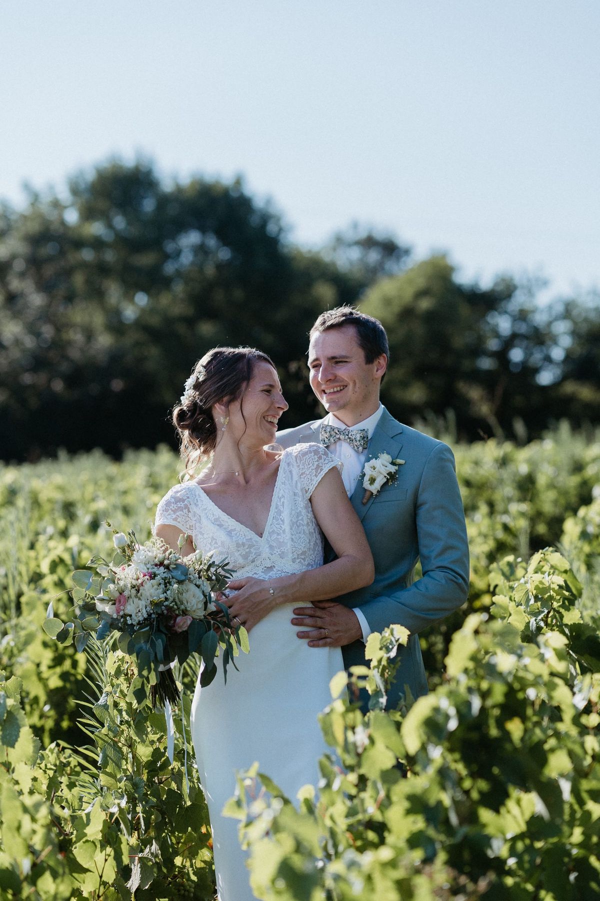 Bride and groom portrait standing among vineyard rows at golden hour
