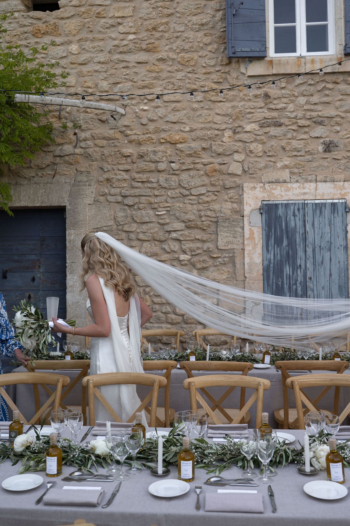 Louise beside the long reception table, her veil lifting in the breeze