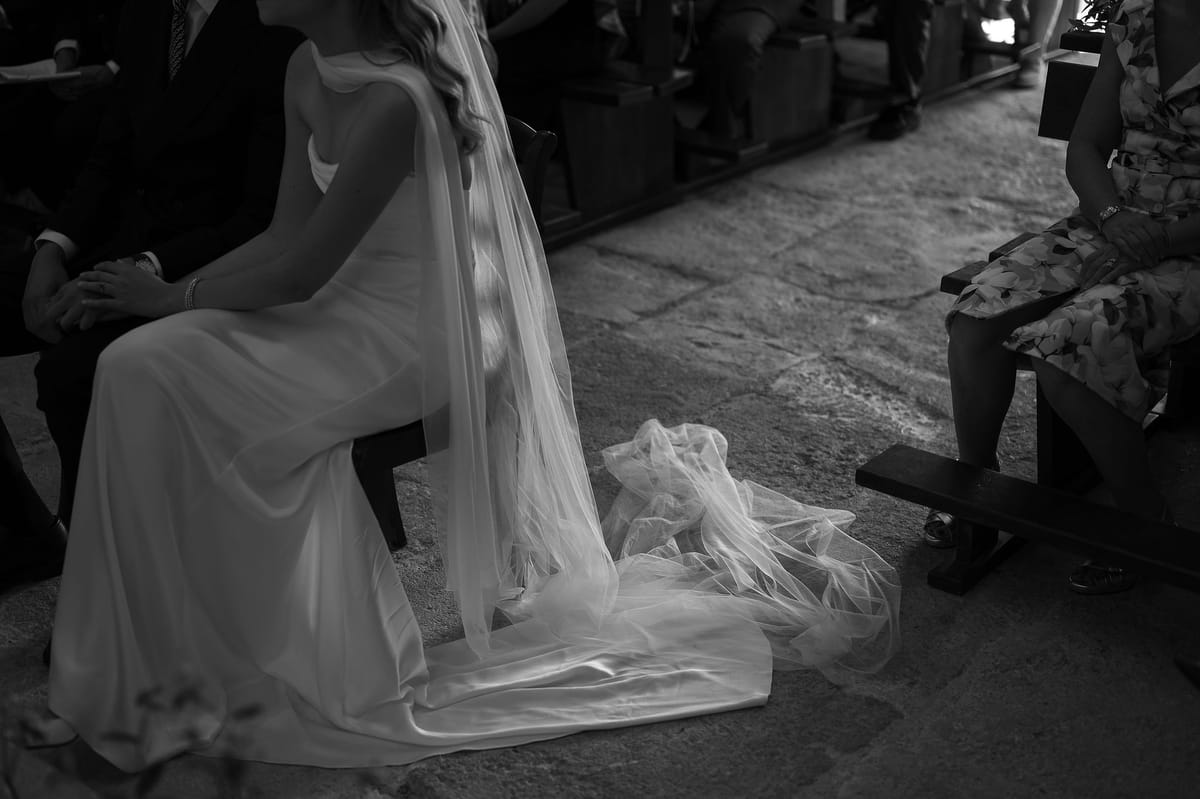 Black and white photograph of Louise seated in the church, her veil pooling on the stone floor