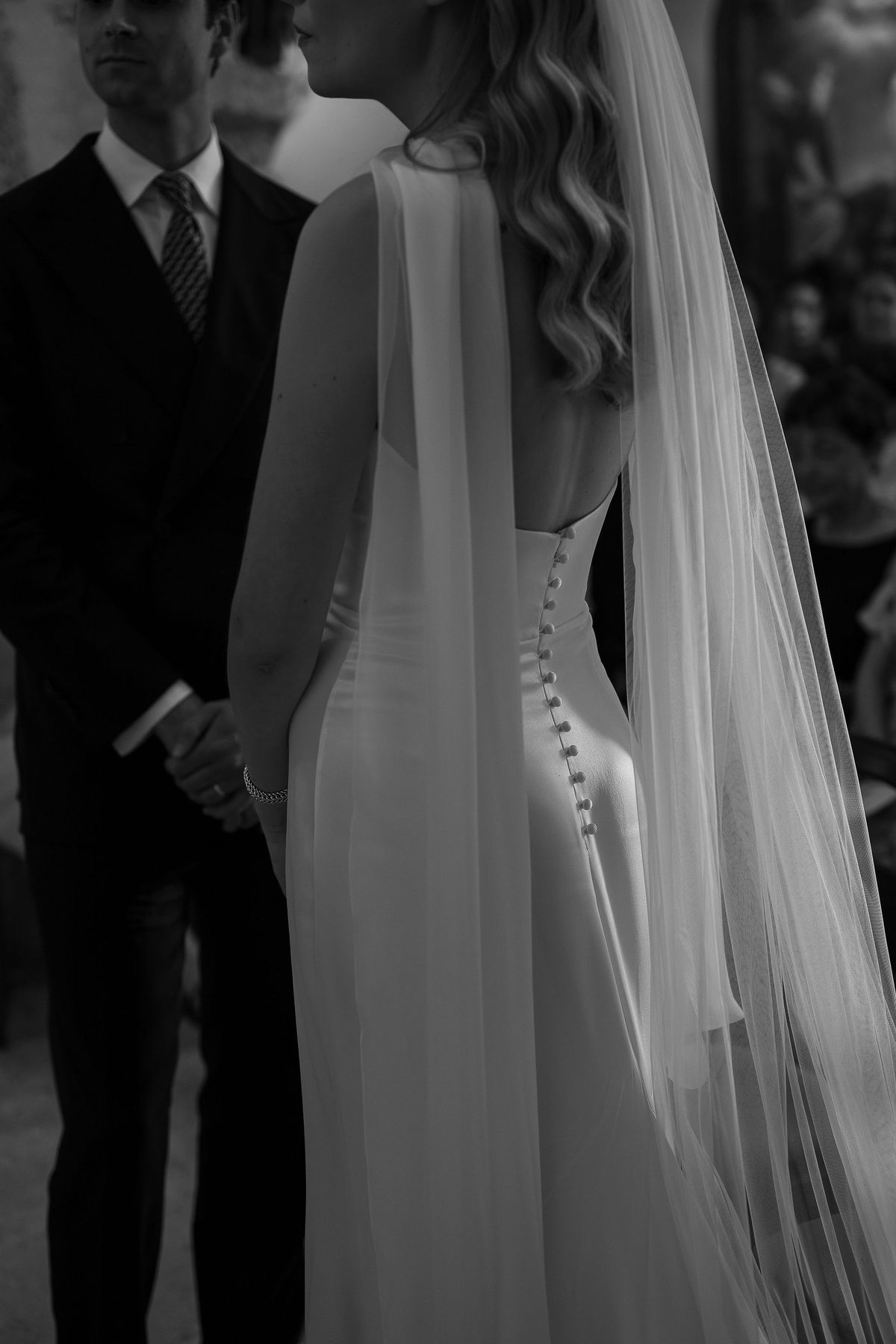 Black and white photograph of the back of Louise's silk gown and veil during the ceremony