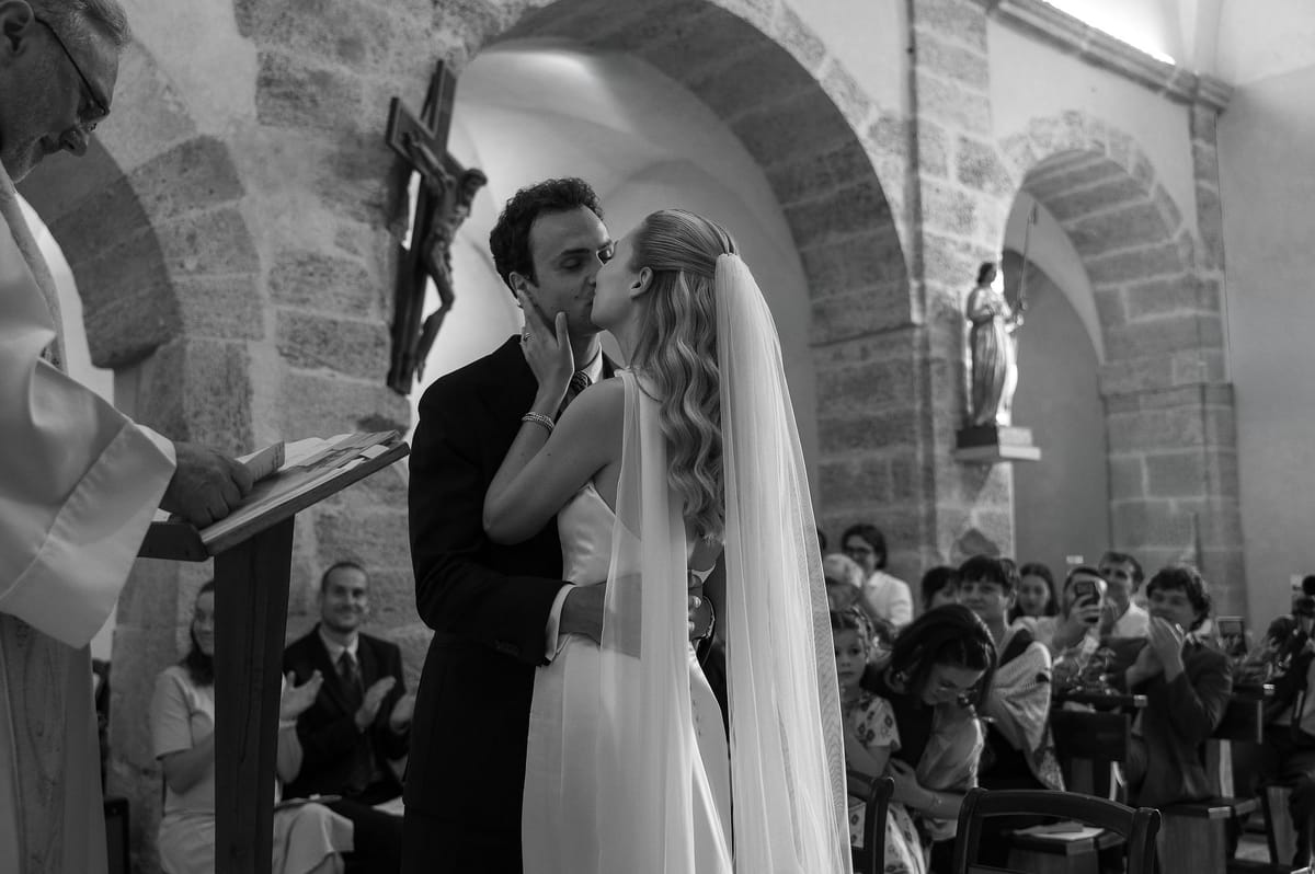 Black and white photograph of Louise and Lucas kissing at the altar of the village church