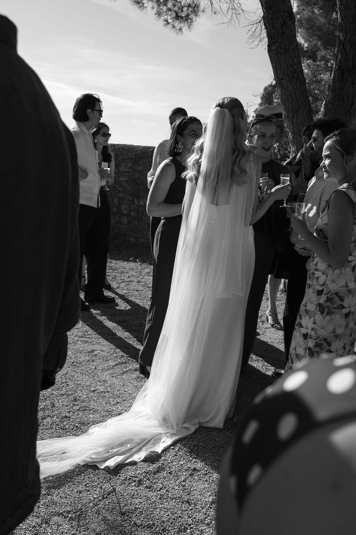Black and white photograph of Louise in her veil with guests outside the village church