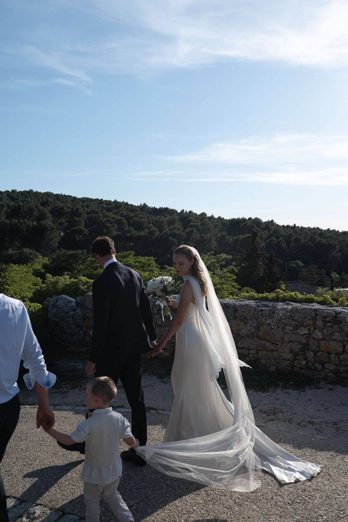 Louise and Lucas walking hand in hand with a child along the village wall above the Luberon valley