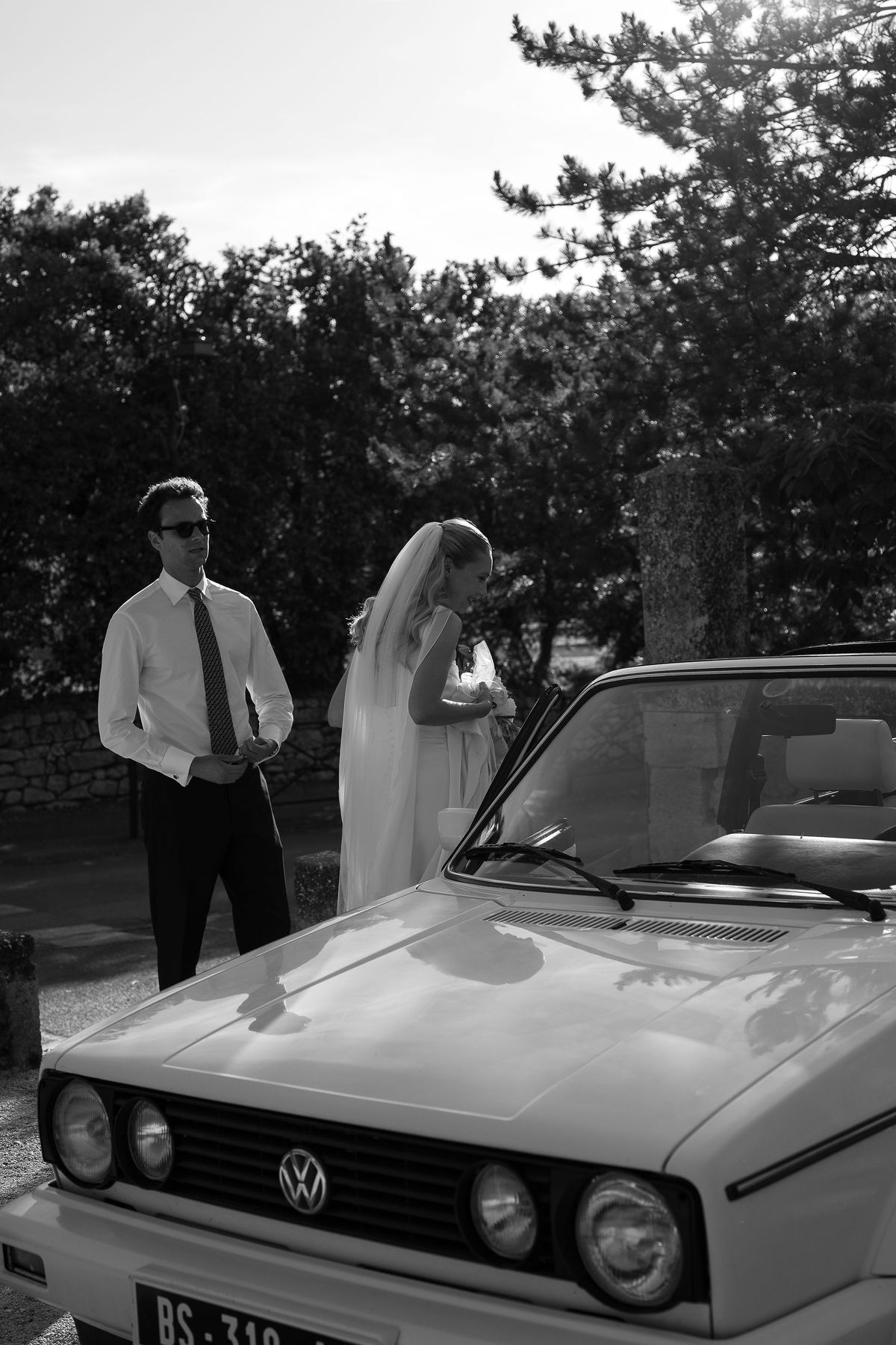 Black and white photograph of Louise beside a vintage convertible in the village