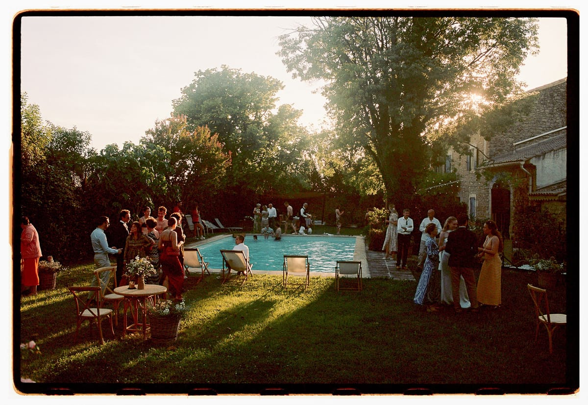 Guests gathered around the swimming pool in the evening light, photographed on film