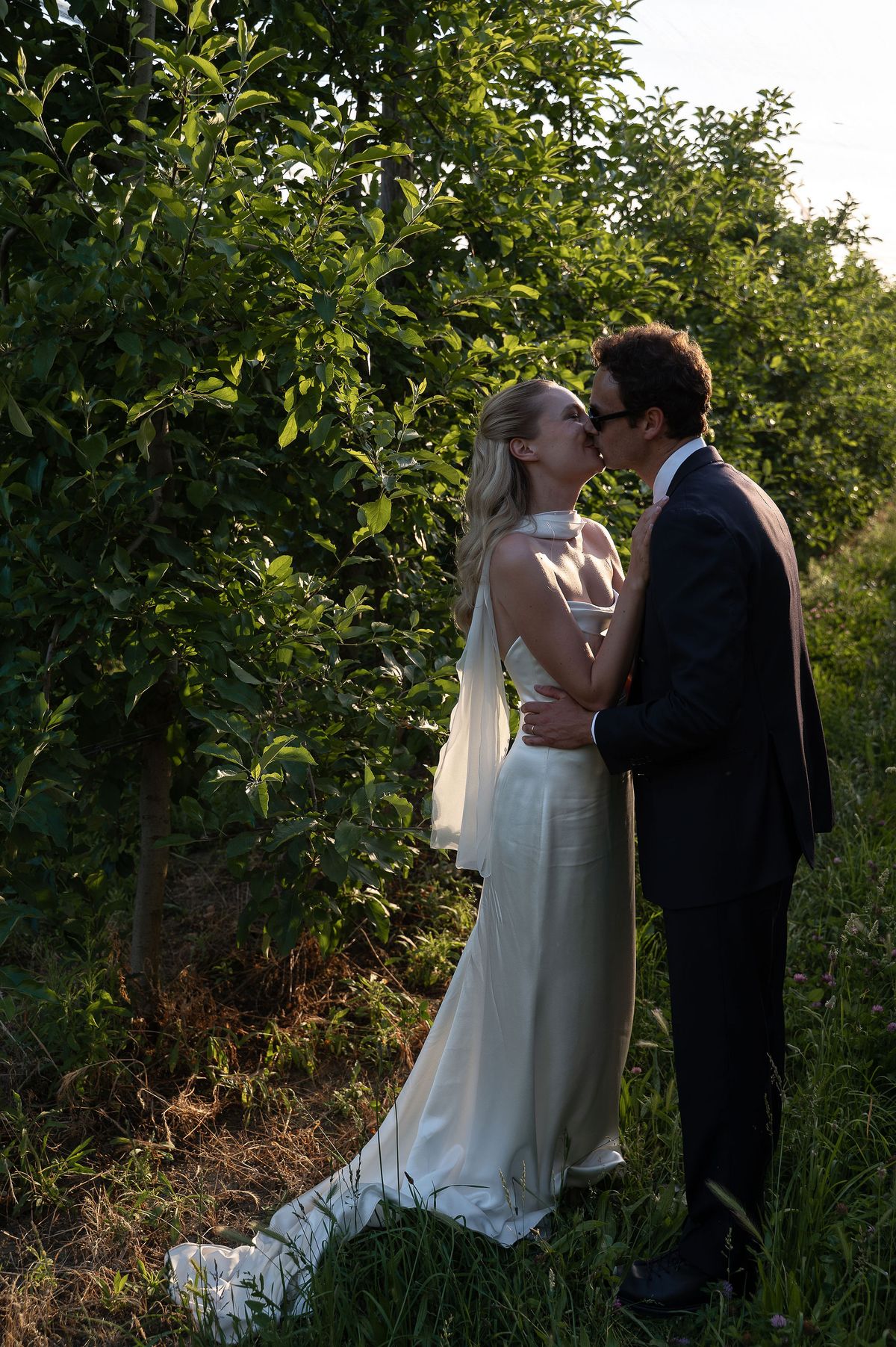 Louise and Lucas standing together among the fruit trees at their Luberon wedding