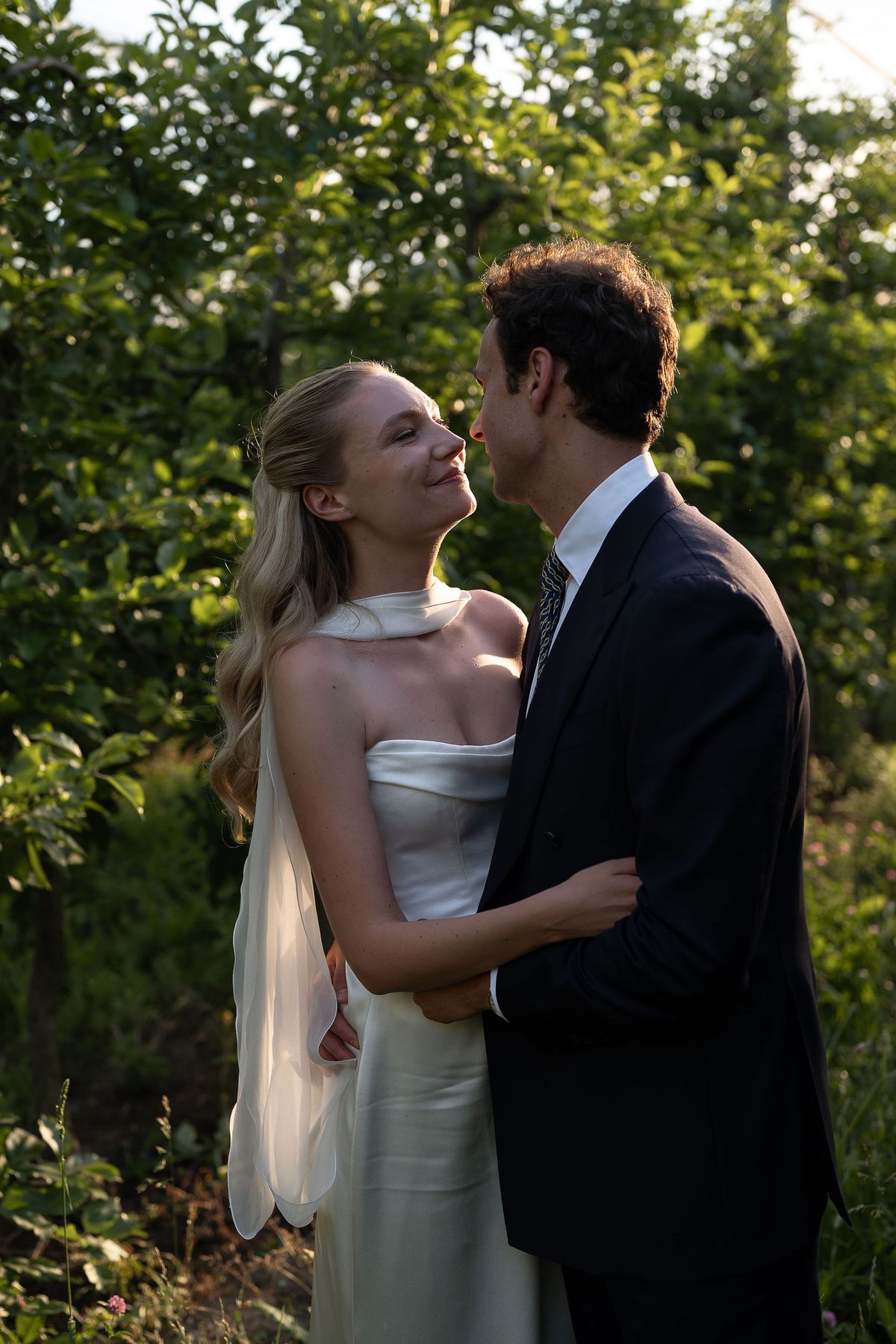 Louise and Lucas embracing among the fruit trees in the evening light