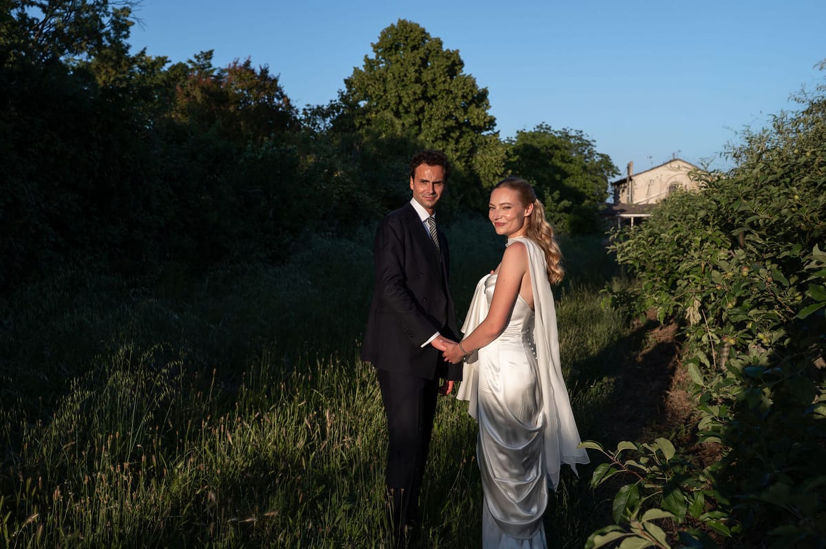 Louise and Lucas holding hands in the long grass of the orchard