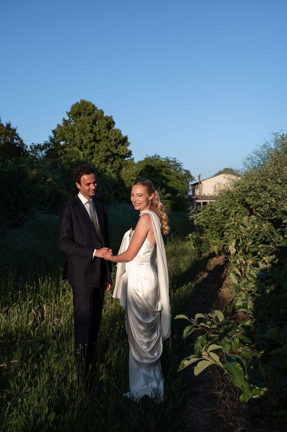 Louise and Lucas facing each other in the orchard beneath a clear sky