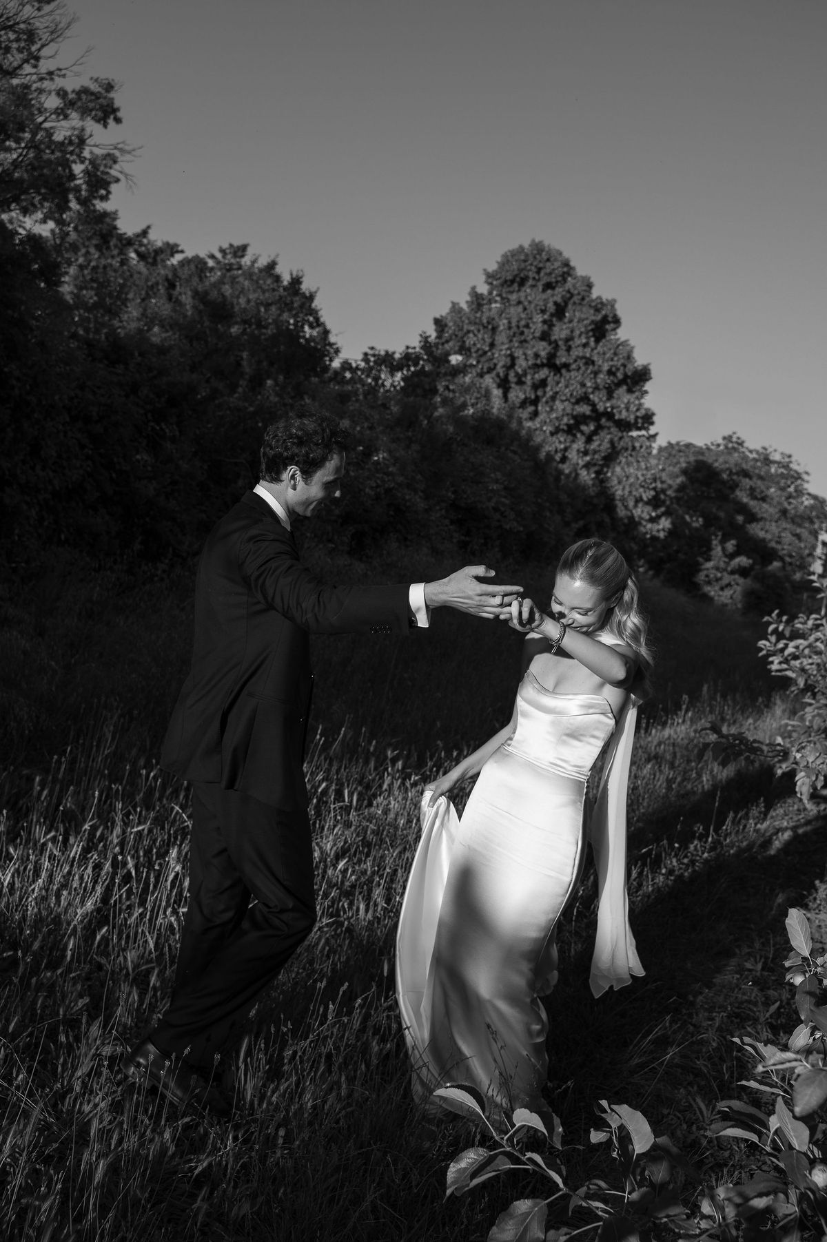 Black and white photograph of Louise and Lucas laughing together in the orchard
