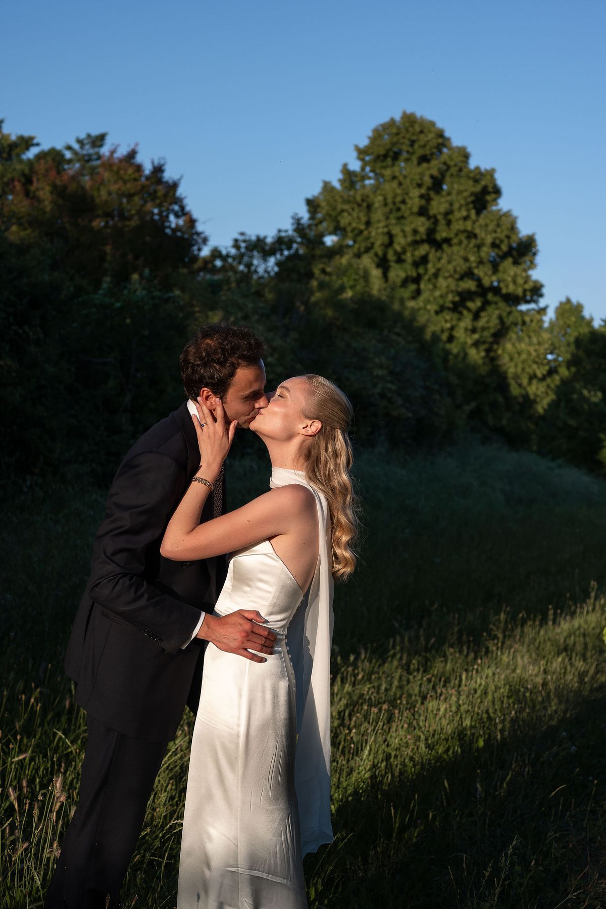 Louise and Lucas leaning together in the long grass of the orchard