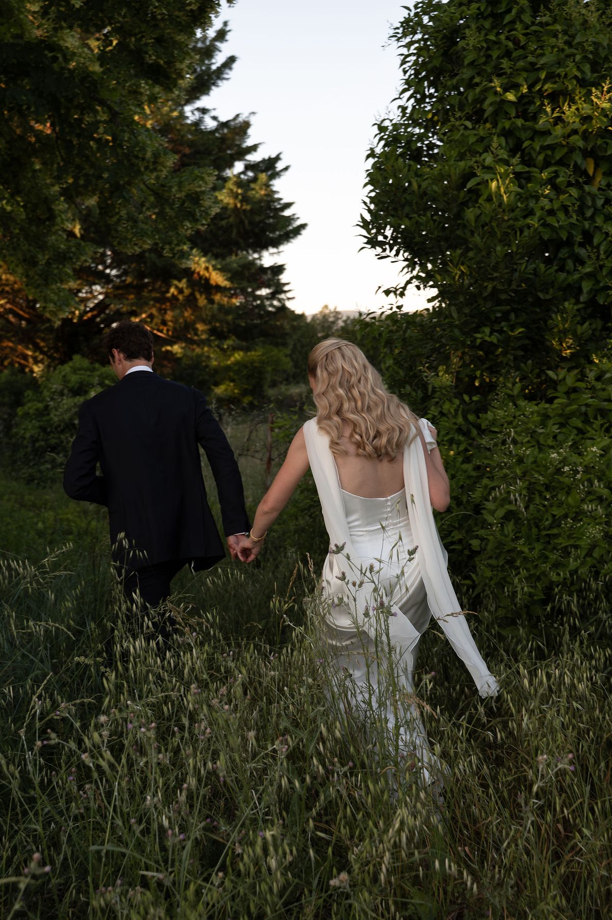 Louise and Lucas walking through the orchard, her silk train trailing behind