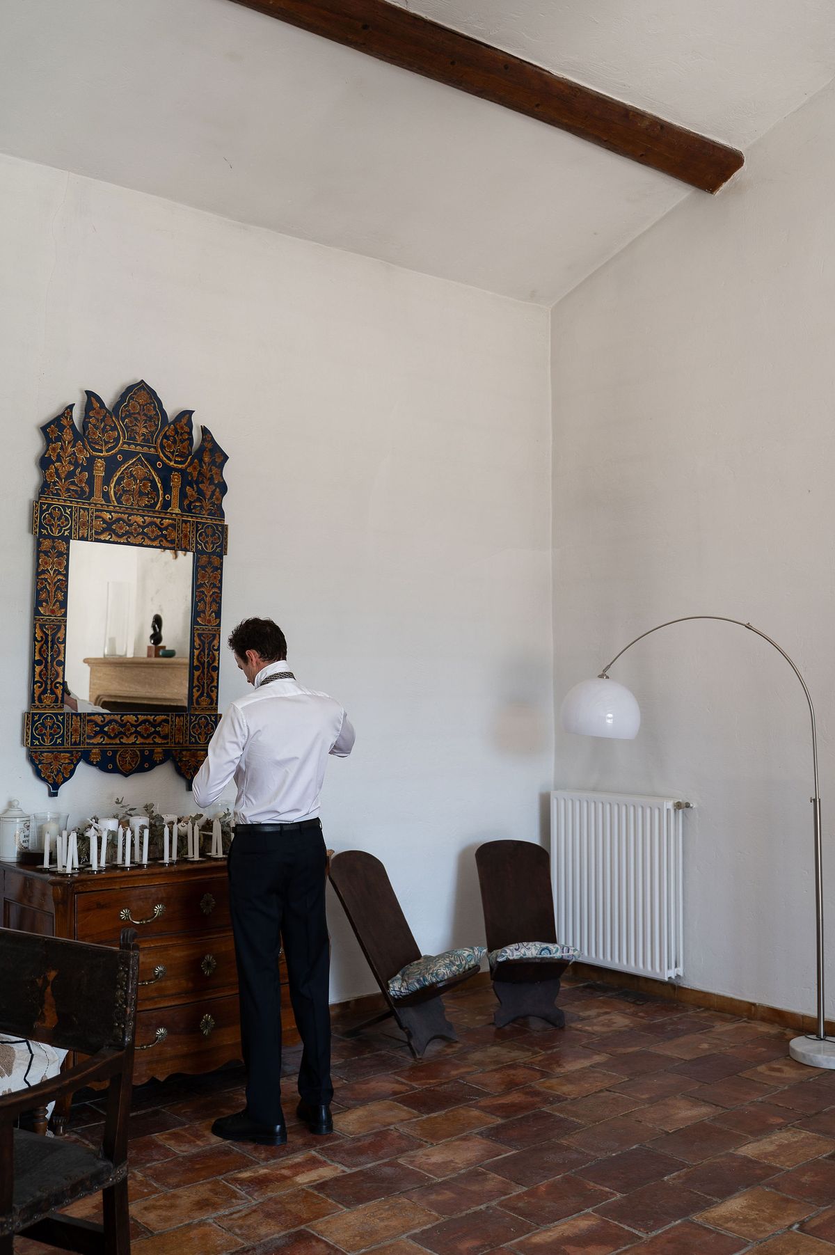 Lucas dressing in front of a carved wooden mirror before the ceremony