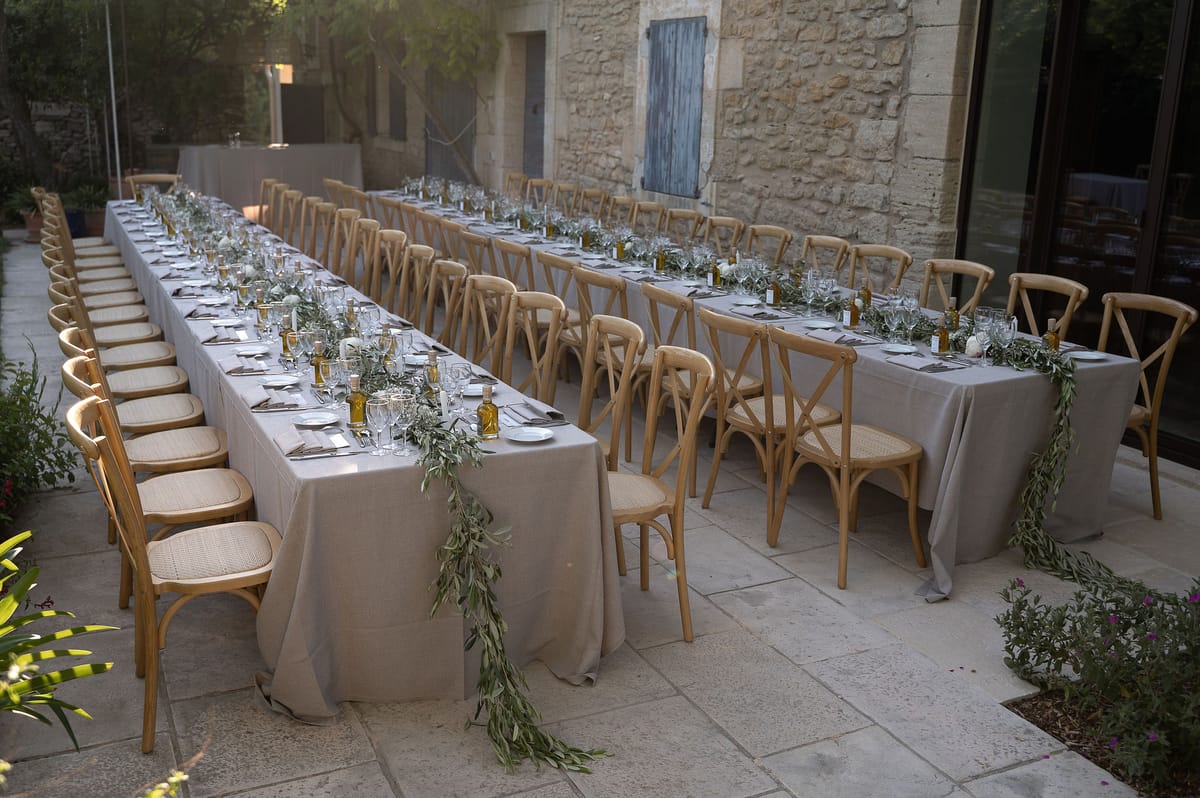 Long tables dressed with linen and an olive branch runner in the garden of the family home
