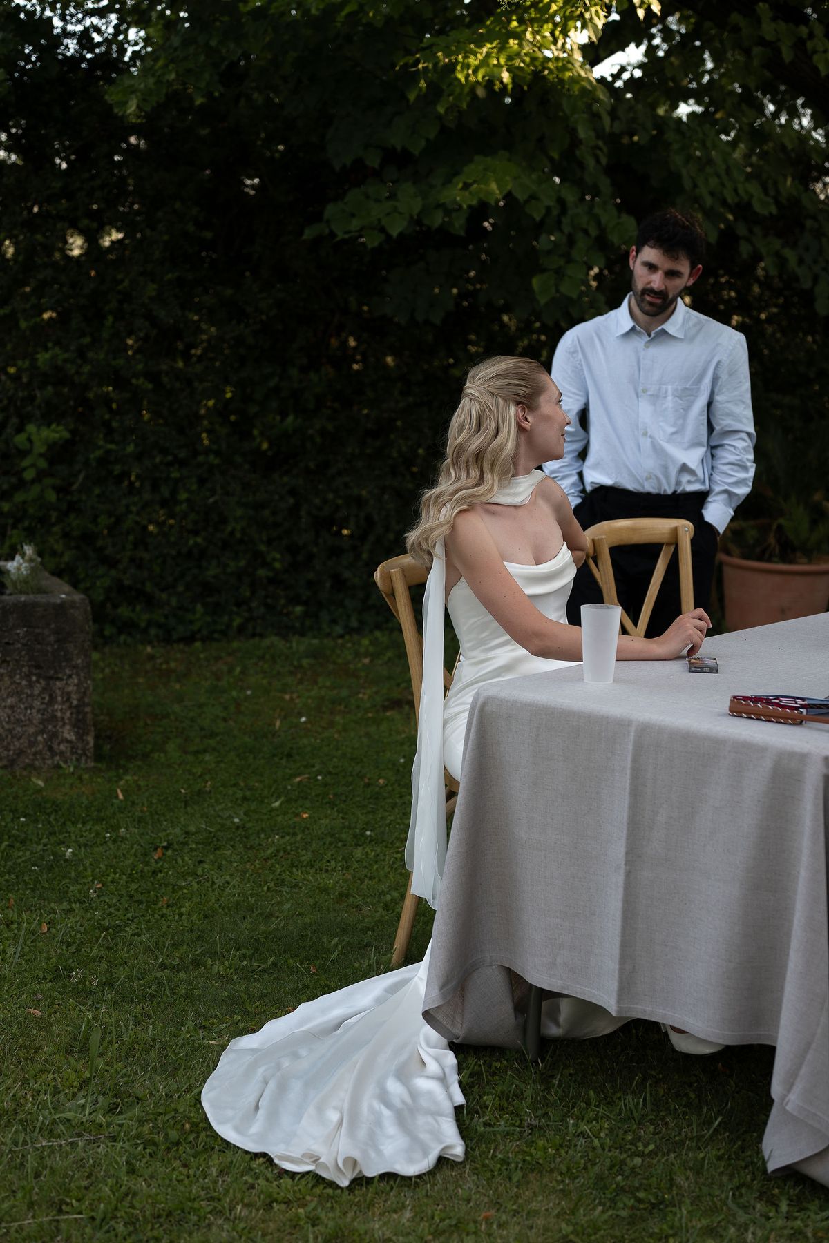Louise seated at a linen draped table in the garden during the reception