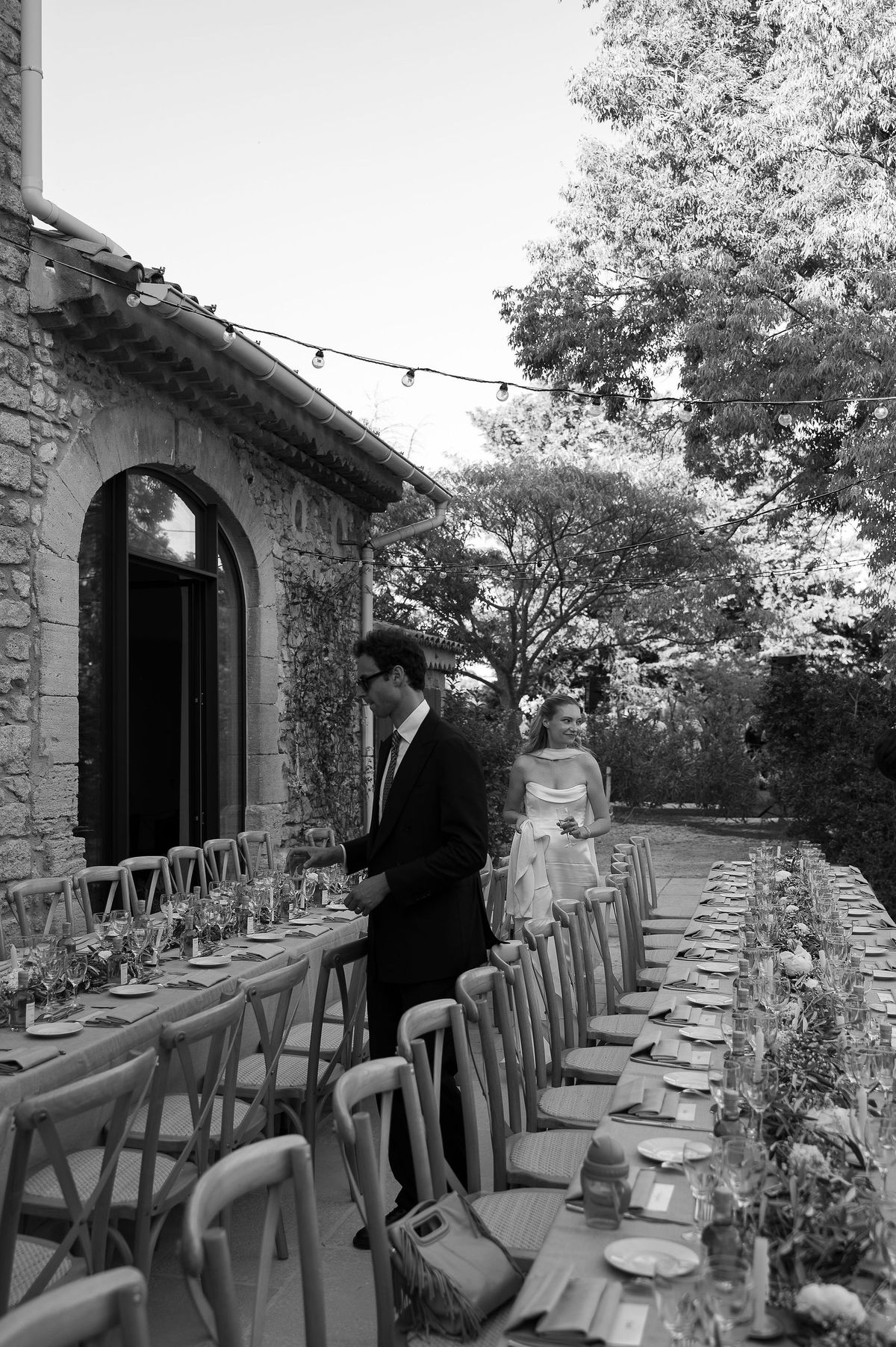 Black and white photograph of the long reception table set beside the stone house