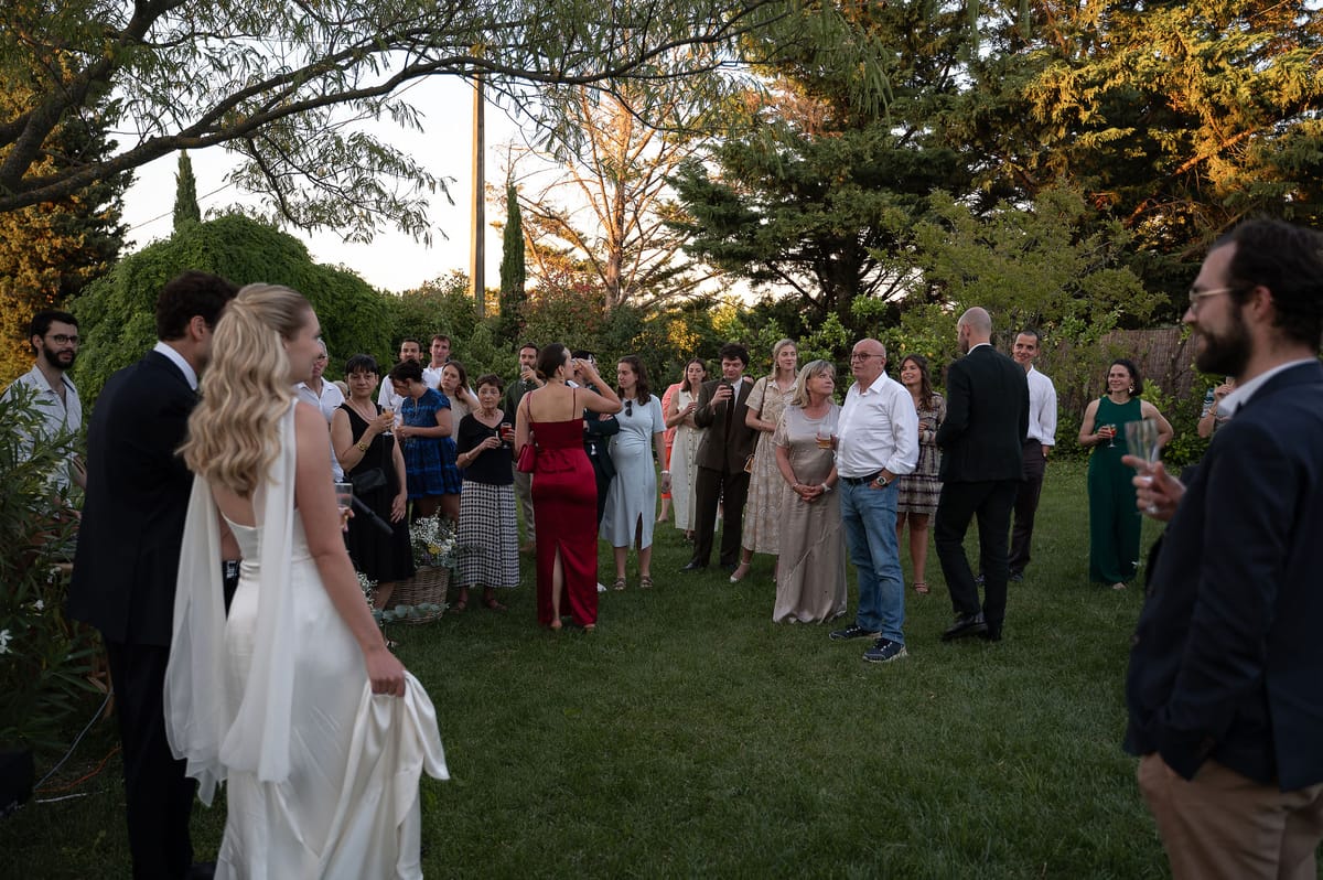Louise and Lucas facing their guests gathered in a semicircle in the garden