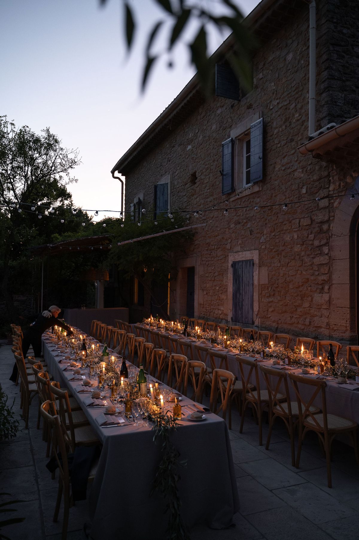 The long table set with candles in the garden as the sky darkens