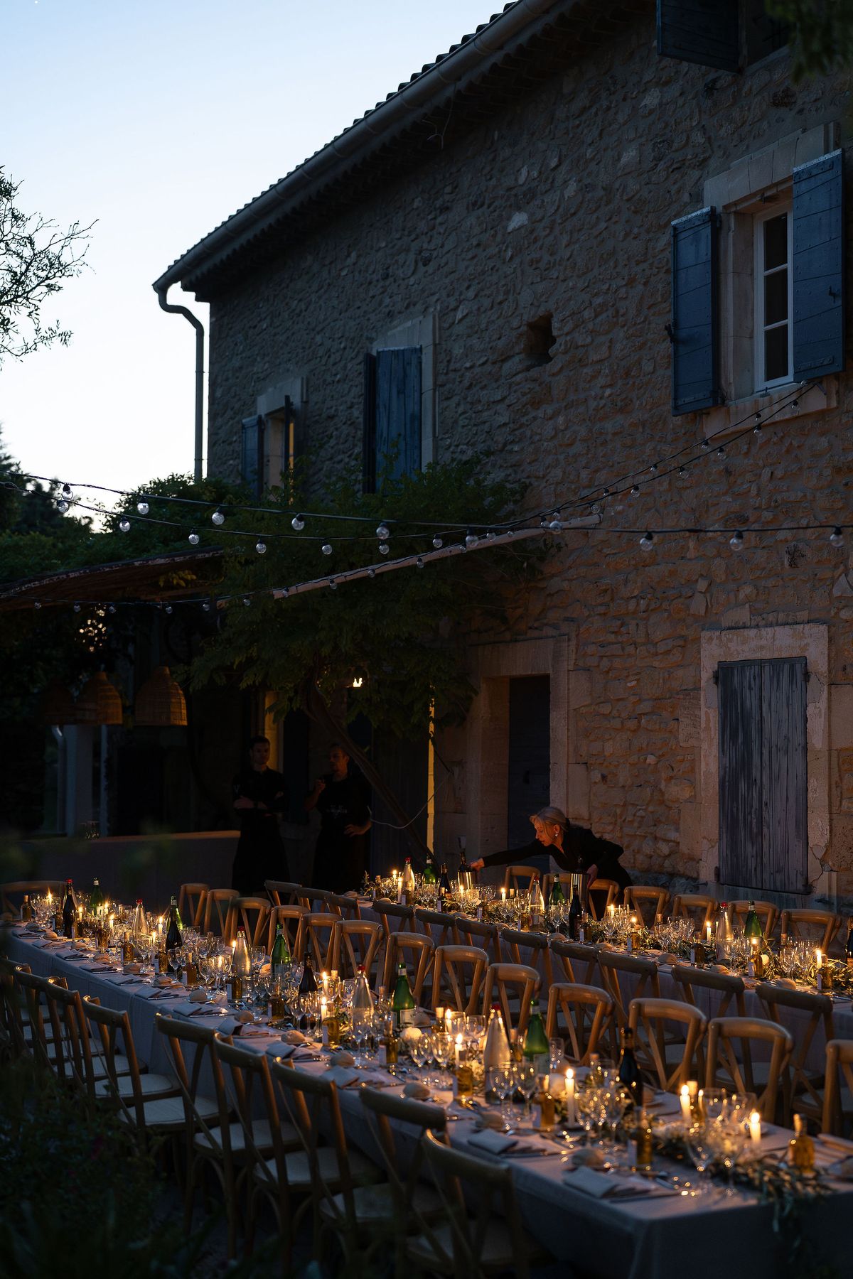 Candlelit reception tables and the lit windows of the family home