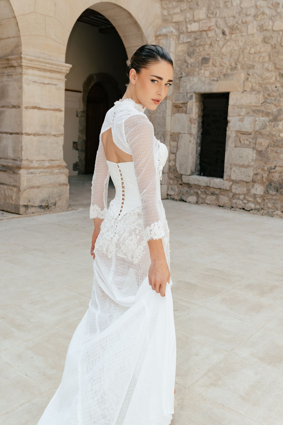 Bride in a corseted lace gown photographed against the stone arches of the convent