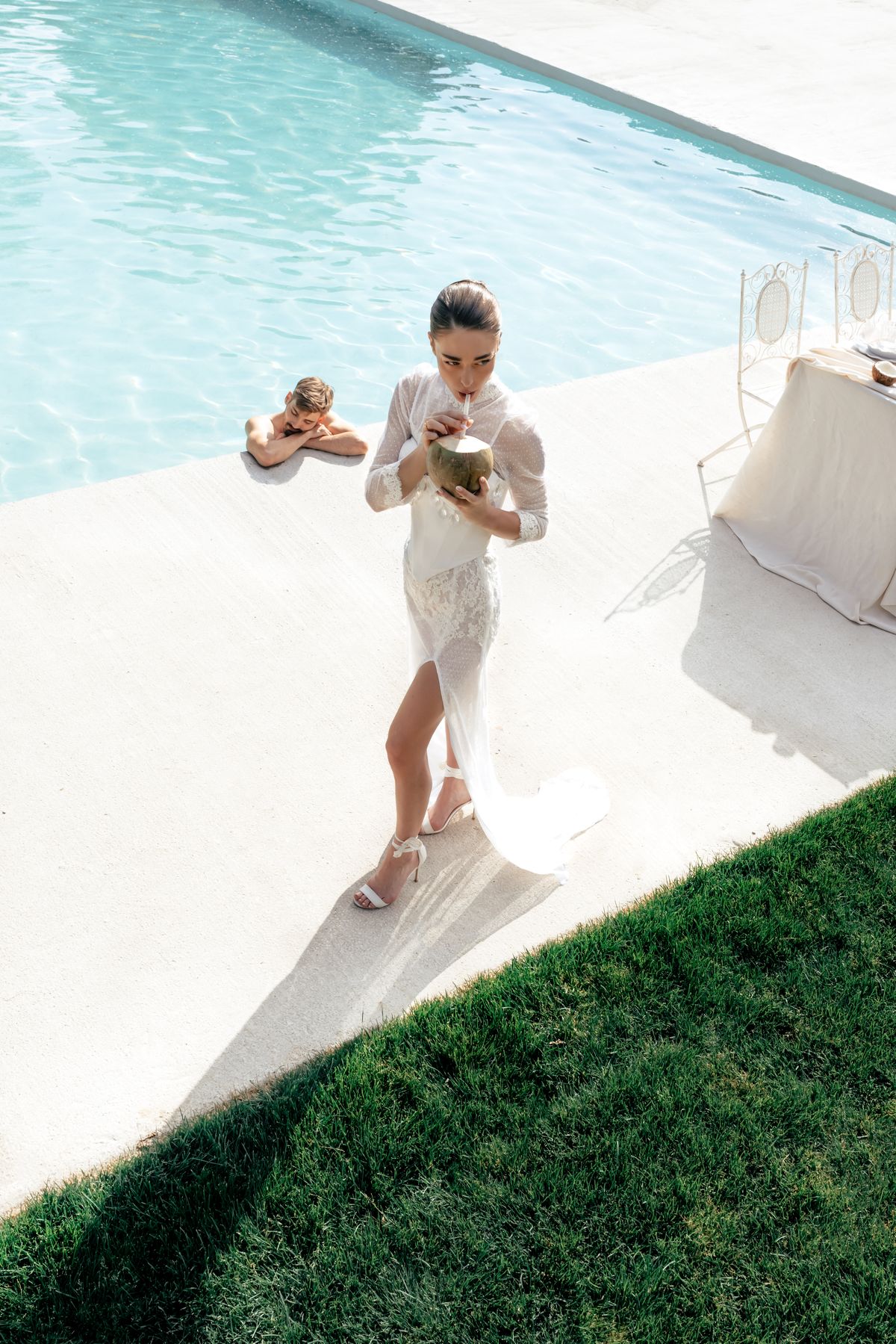Bride walking along the poolside terrace carrying a coconut cocktail
