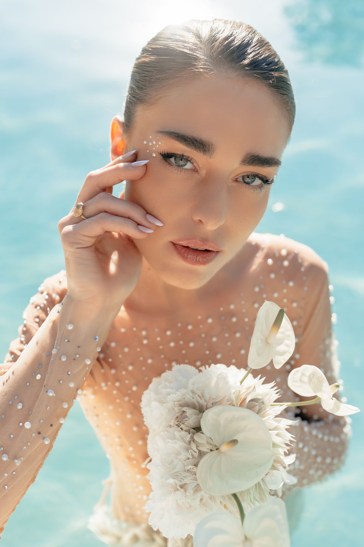 Bride in the pool holding a white anthurium bouquet against her shoulder