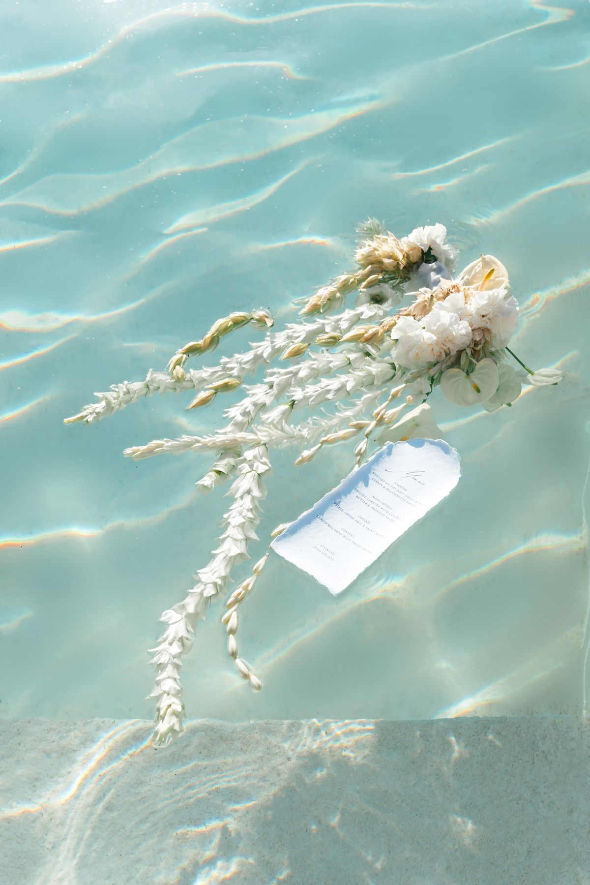 Bridal bouquet and stationery floating on the surface of the pool