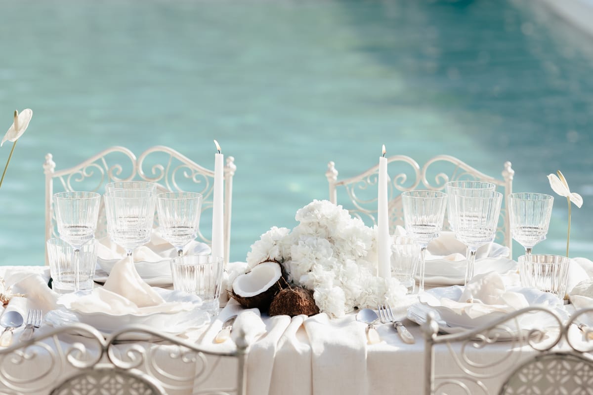 Table detail with coconut shells, white florals and cut crystal beside the pool