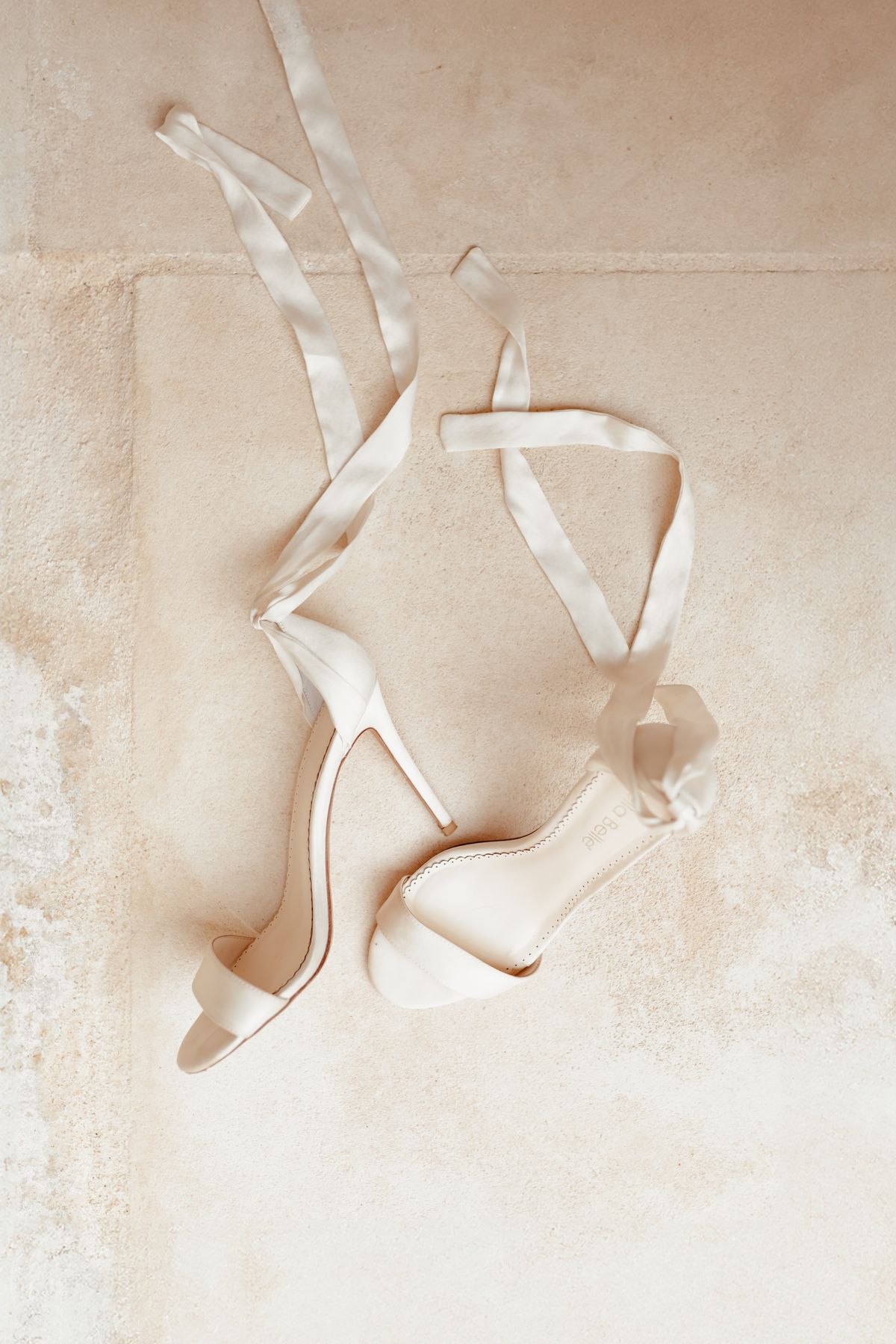 Satin ankle-tie bridal heels photographed on warm stone