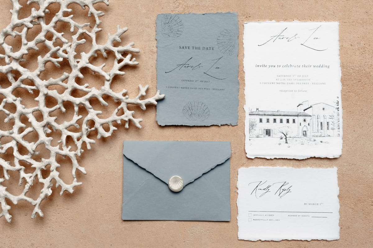 Blue-grey deckle-edged stationery suite with shell wax seal and white coral