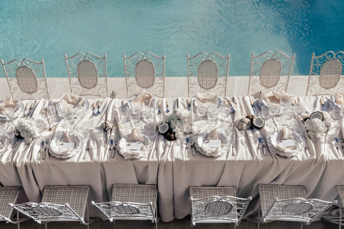 Long reception table dressed in ivory linen beside the pool at Couvent Notre-Dame des Prés