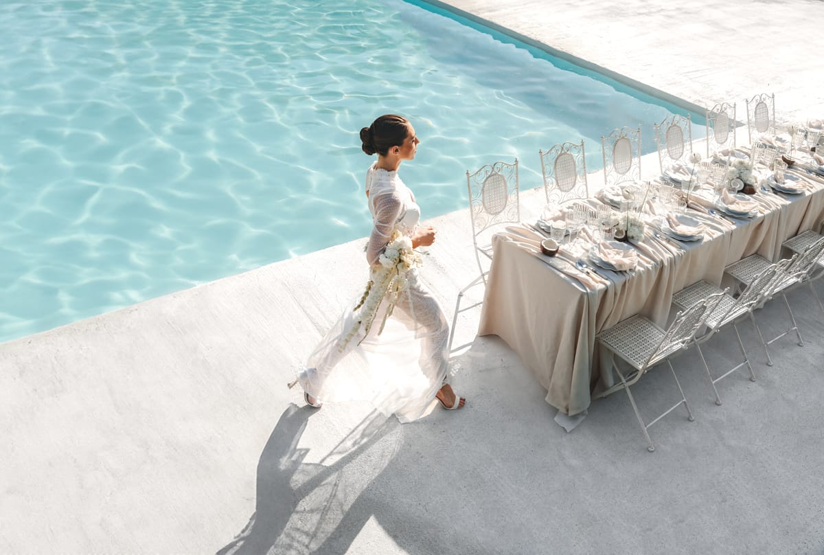 Bride walking the length of the poolside reception table