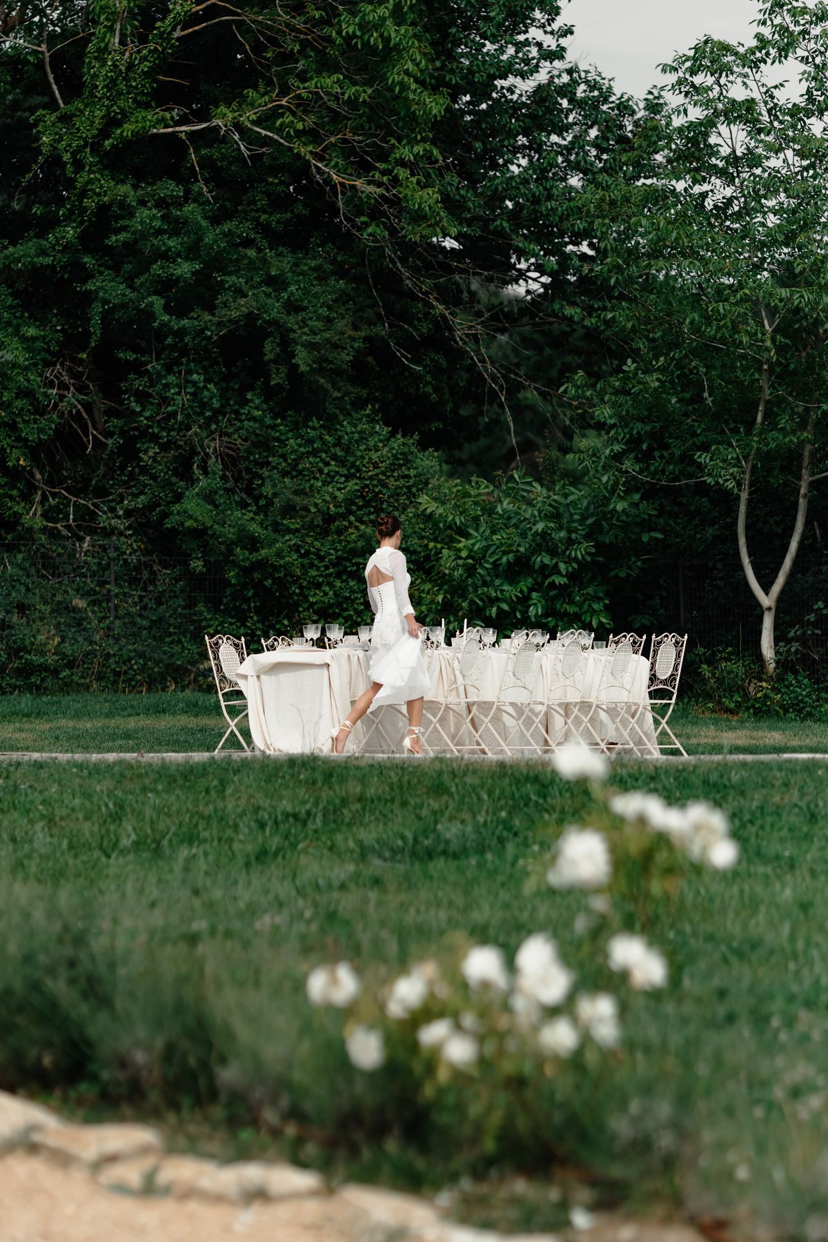 Bride walking towards the long table set on the lawn in the grounds of Couvent Notre-Dame des Prés