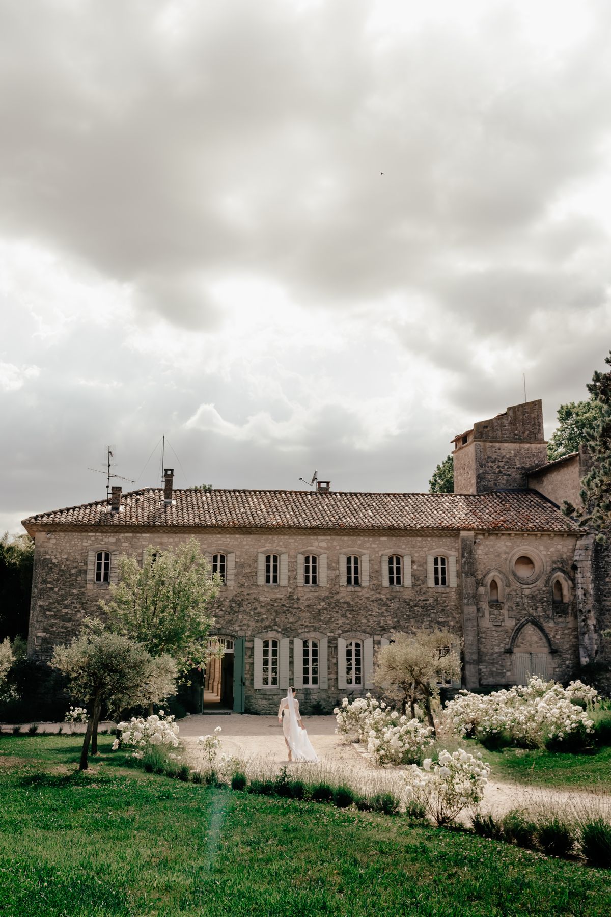 Wide view of the stone facade and gardens at Couvent Notre-Dame des Prés in summer