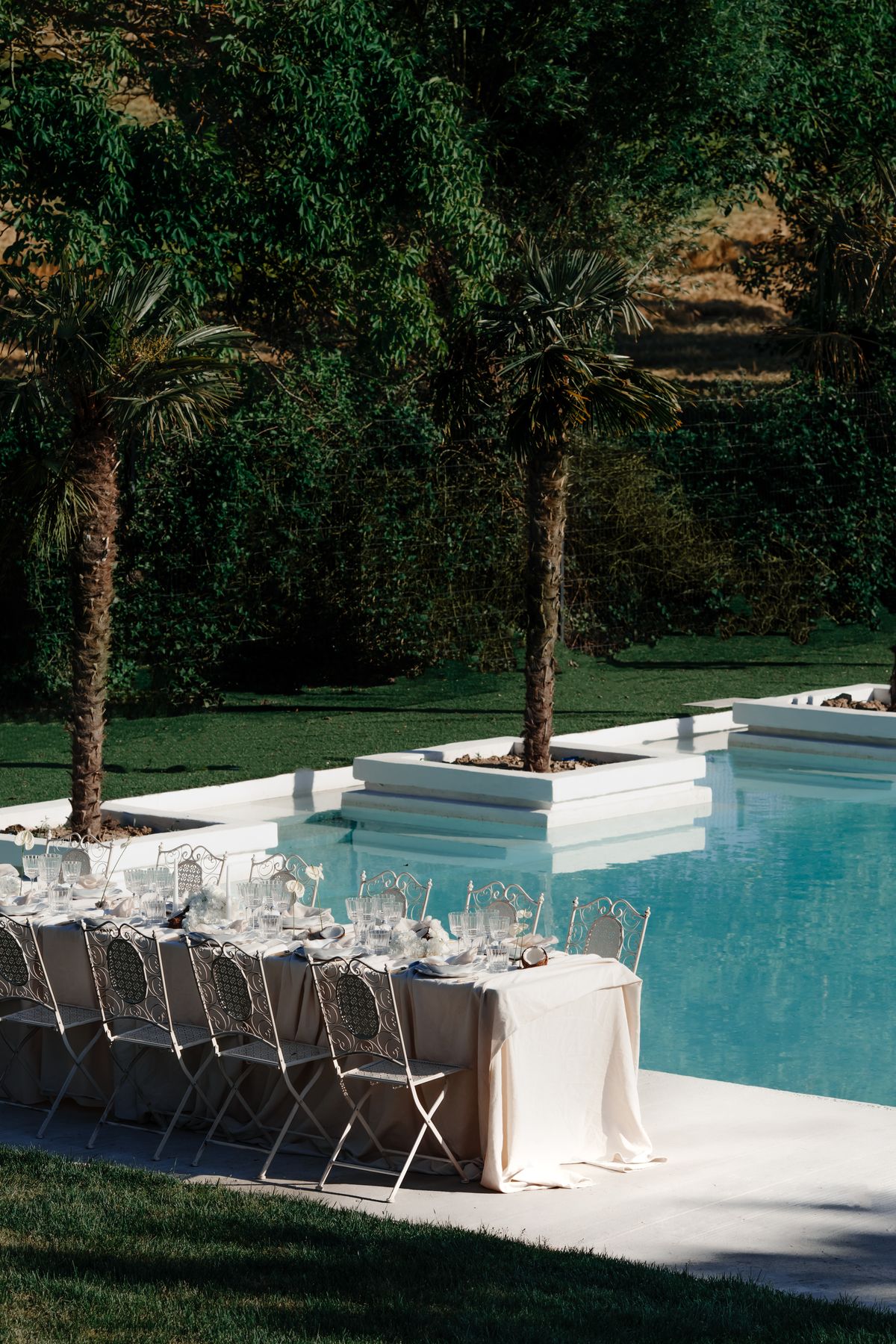 Wide view of the pool, palms and long table in the grounds of Couvent Notre-Dame des Prés