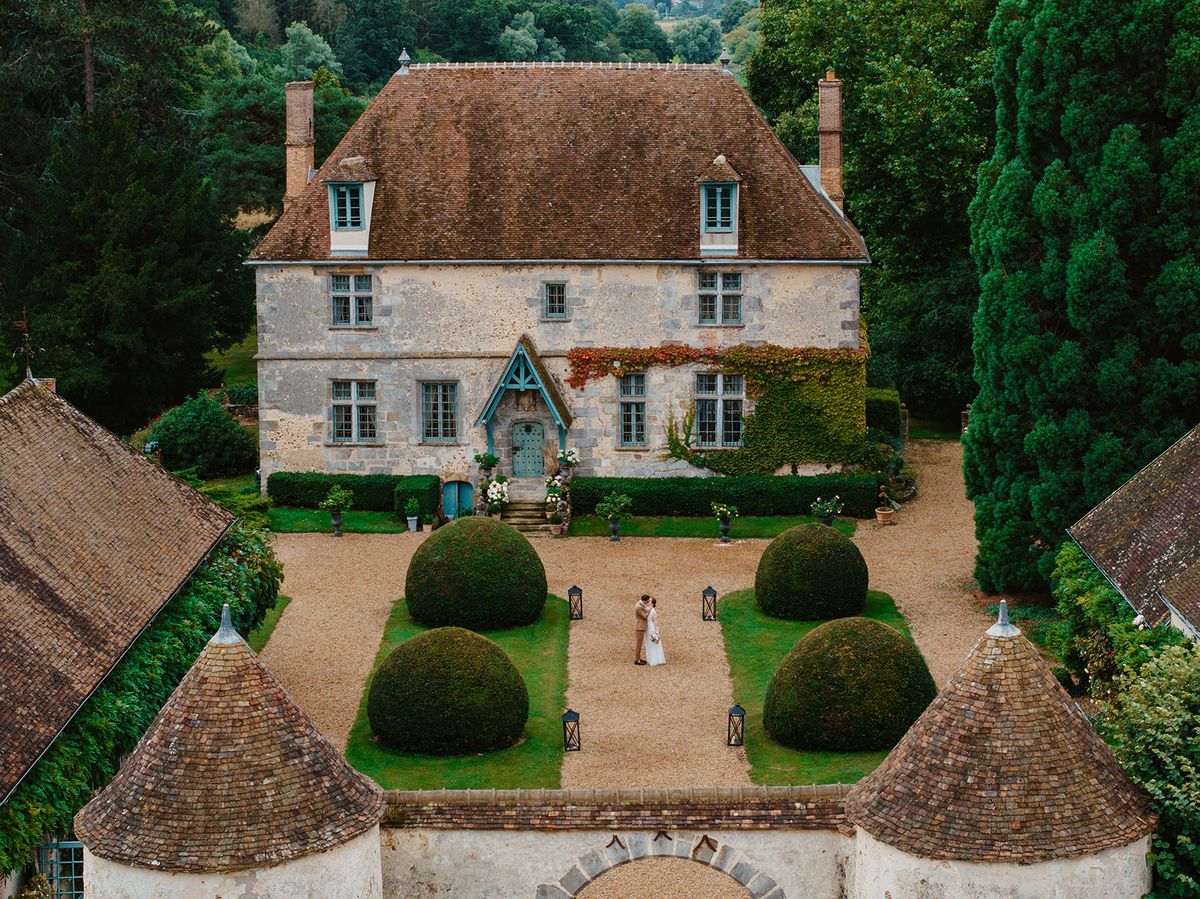 Aerial view of the manor's forecourt with a couple embracing among clipped topiary spheres