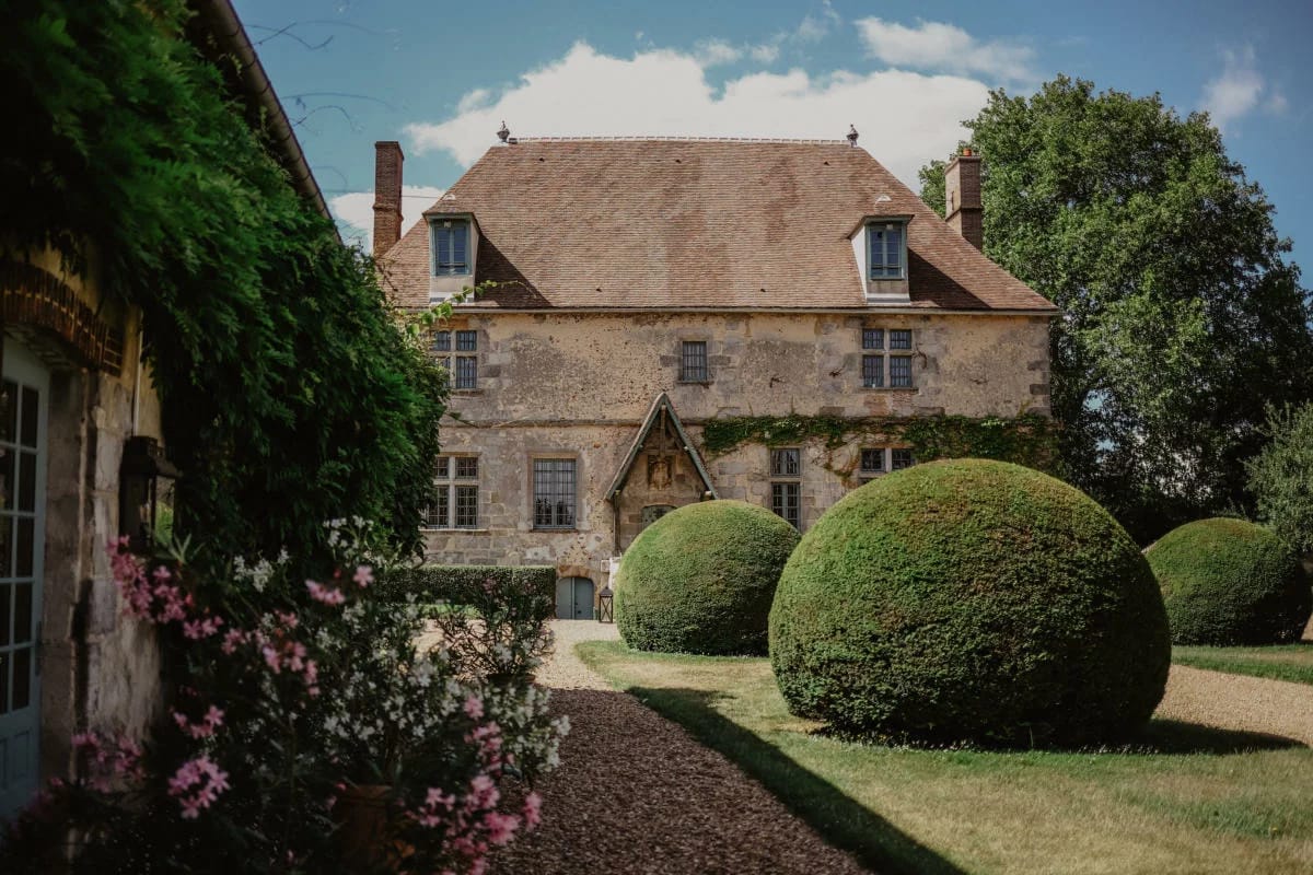 Manor facade and topiary-lined forecourt in full sun