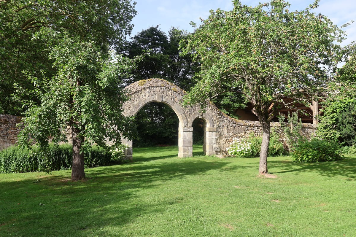 Stone garden archway framed by apple trees on the manor's grounds