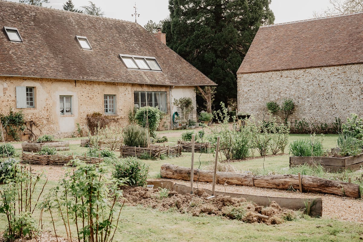 Kitchen garden with raised vegetable beds beside a secondary property building