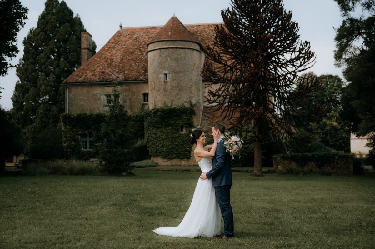 Couple portrait on the lawn with the estate's round stone dovecote tower behind them