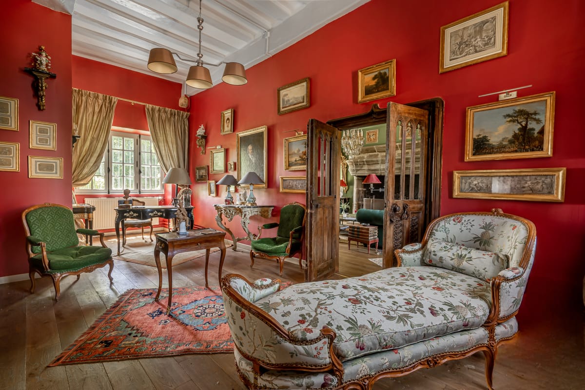 Interior red-walled salon with gilt-framed paintings, antique furniture and a chaise longue