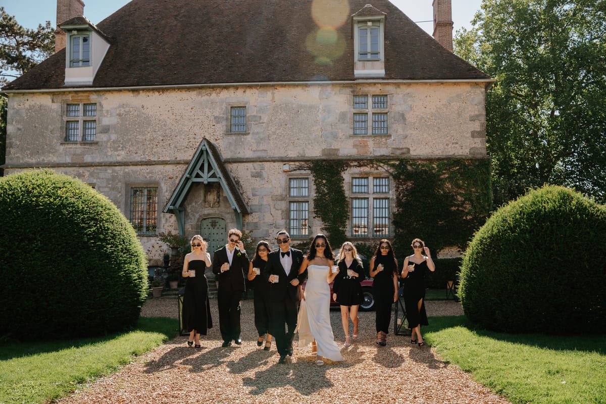Wedding party walking across the gravel forecourt toward the manor's facade