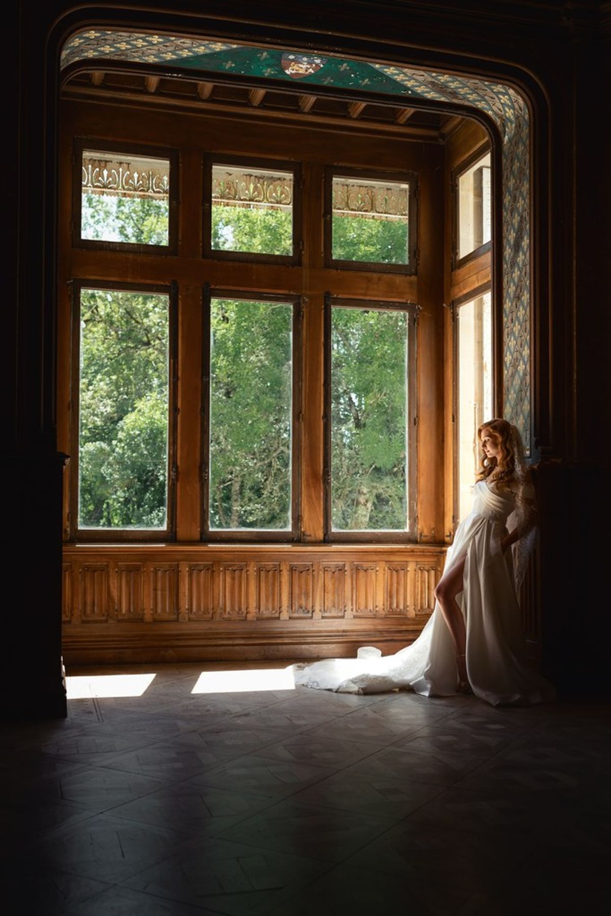 Blush and fuchsia styled shoot at Château du Causse, Occitanie, the bride seated in a wood-panelled window bay