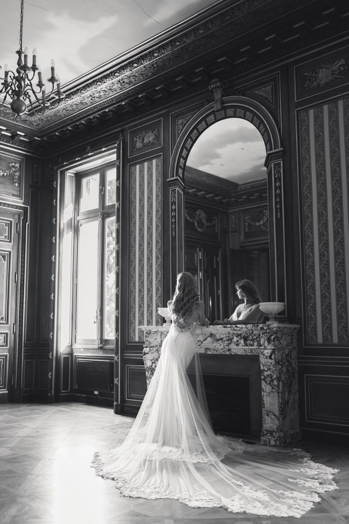 Blush and fuchsia styled shoot at Château du Causse, Occitanie, the bride by a marble fireplace and mirror, in black and white
