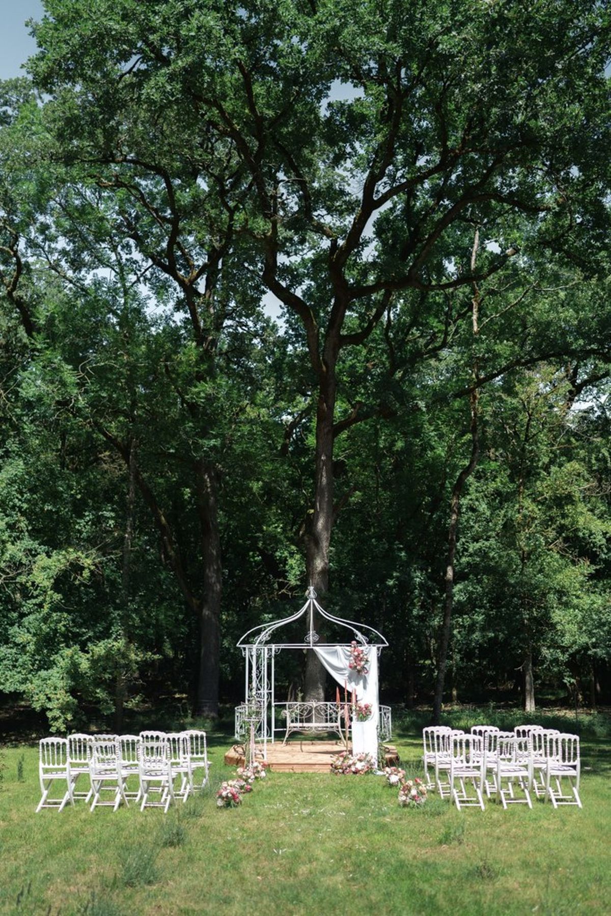 Blush and fuchsia styled shoot at Château du Causse, Occitanie, a white wrought-iron gazebo hung with drapery, with rows of chairs on the lawn