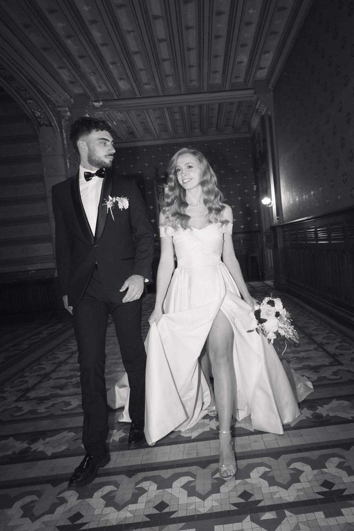 Blush and fuchsia styled shoot at Château du Causse, Occitanie, the couple walking through a panelled room, in black and white
