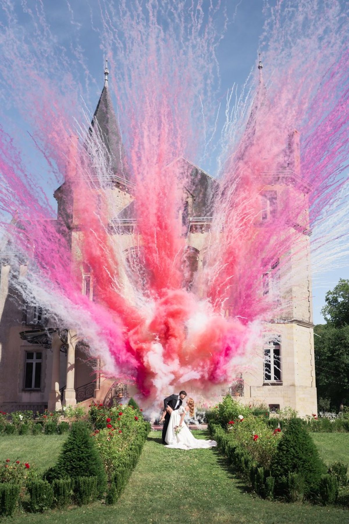 Blush and fuchsia styled shoot at Château du Causse, Occitanie, pink daytime fireworks rising in front of the château turrets