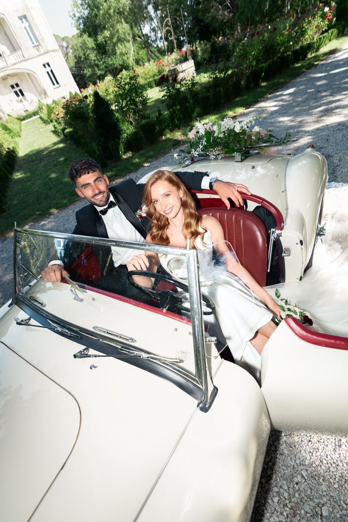 Blush and fuchsia styled shoot at Château du Causse, Occitanie, the couple seated in the vintage car